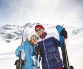 Feliz casal caucasiano carregando esquis na montanha — Fotografia de Stock