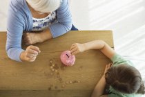 Older woman and granddaughter filling piggy bank — Stock Photo