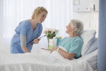 Медсестра і старіння пацієнт розмовляє в лікарняній кімнаті — стокове фото
