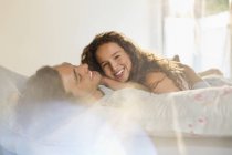 Jeune couple heureux se détendre ensemble au lit — Photo de stock