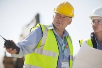 Business people in hard hats talking on site — Stock Photo
