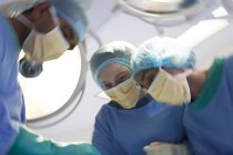 Surgeons bent over patient in operating room — Stock Photo