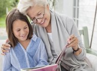 Жінка і онука читають на ганку гойдалки — стокове фото