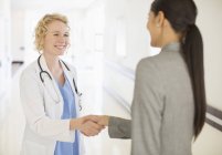 Doctor and businesswoman handshaking in hospital corridor — Stock Photo