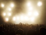 Силуэт толпы, смотрящей освещаемую сцену на музыкальном фестивале — стоковое фото