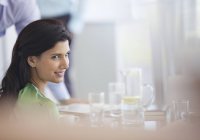 Бізнес-леді посміхається за столом зустрічі в сучасному офісі — стокове фото