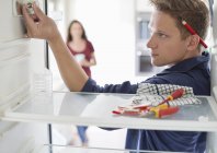 Skillful caucasian electrician working on fridge in home — Stock Photo
