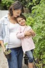 Pregnant mother and daughter gardening together — Stock Photo
