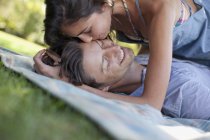 Couple affectueux pose sur la couverture dans l'herbe — Photo de stock