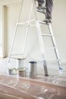 Abgeschnittenes Bild eines Mannes, der auf Leiter klettert, um Raum zu malen — Stockfoto