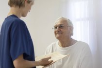 Медсестра розмовляє зі старшим пацієнтом у лікарняній кімнаті — стокове фото