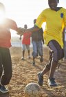 Chicos africanos jugando al fútbol juntos en el campo de tierra - foto de stock