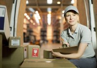 Delivery girl checking boxes in van — Stock Photo