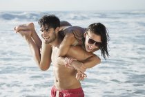 Glücklicher Mann trägt Frau am Strand — Stockfoto