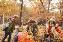 Famiglia che gioca in foglie di autunno in parco — Foto stock