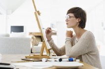 Жінка малює на мольберті за столом — стокове фото