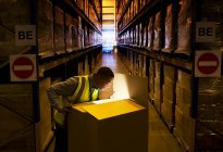 Arbeiter öffnet glühende Schachtel in Lagerhalle — Stockfoto