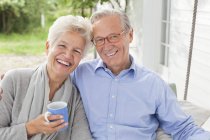 Smiling couple sitting on porch swing — Stock Photo
