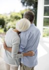 Rückansicht eines Senioren-Paares, das sich auf der Terrasse umarmt — Stockfoto