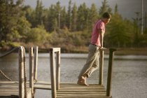 Серединний чоловік стоїть на перилах причалу над озером — стокове фото