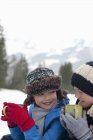 Primer plano de niños felices bebiendo chocolate caliente en el campo cubierto de nieve - foto de stock