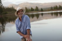 Усміхнений зрілий чоловік позує на березі озера — стокове фото