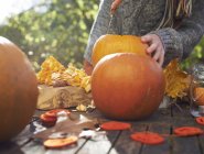 Teenage boy carving pumpkins outdoors — Stock Photo