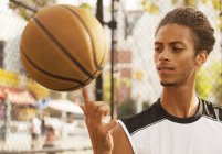 Чоловік обертається баскетболом на пальці т-корт — стокове фото