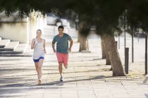 Couple running through city streets together — Stock Photo