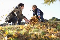 Father and son playing in autumn leaves — Stock Photo