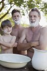 Ritratto di uomini multi-generazione con braccia incrociate e crema da barba sui volti — Foto stock