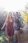 Couple playing with water guns in backyard — Stock Photo