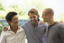 Jóvenes atractivos hombres sonrientes hablando al aire libre - foto de stock