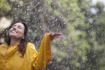 Glückliche Frau steht mit ausgestreckten Armen im Regen — Stockfoto