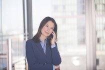 Businesswoman talking on cell phone in office — Stock Photo