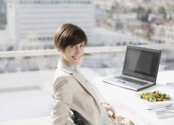 Porträt einer lächelnden Geschäftsfrau mit Mittagessen am Schreibtisch — Stockfoto