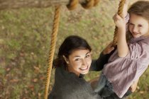 Portrait of smiling mother and daughter on swing — Stock Photo