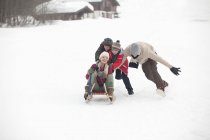 Happy family sledding in snowy field — Stock Photo