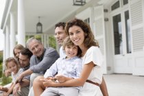 Famille heureuse se détendre sur le porche ensemble — Photo de stock