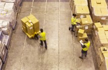 Рабочие перевозят коробки на складе — стоковое фото