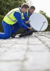 Workers installing satellite dish on roof — Stock Photo