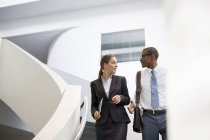 Бізнесмен і бізнес-леді говорять про сучасні сходи в офісі — стокове фото