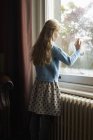 Visão traseira da menina olhando para fora da janela — Fotografia de Stock