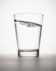 Água inclinada em vidro sobre fundo branco — Fotografia de Stock