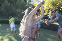 Family playing with water guns in backyard — Stock Photo