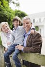 Ehepaar und Enkel lächeln am Holzzaun — Stockfoto