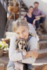 Ritratto di ragazza sorridente che tiene il cucciolo con i genitori sullo sfondo — Foto stock