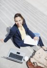 Ritratto di donna d'affari sorridente con scartoffie, caffè e laptop su gradini — Foto stock
