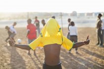 African boy celebrating with soccer jersey on his head in dirt field — Stock Photo