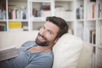 Uomo sorridente che ascolta musica sul divano — Foto stock